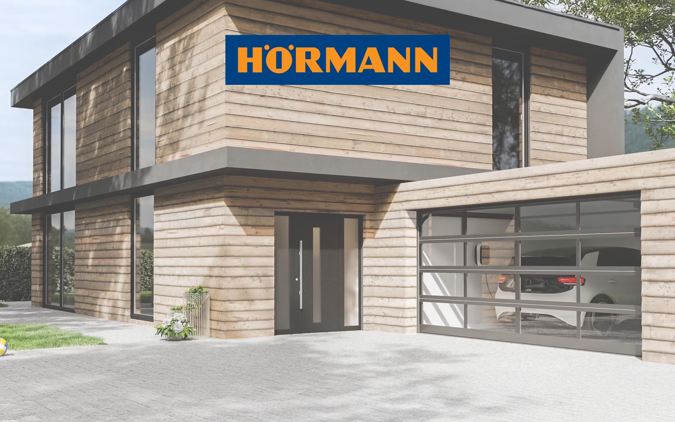 Modern wooden house with large glass surfaces and adjoining garage with sectional door, with the Hörmann logo in the foreground.