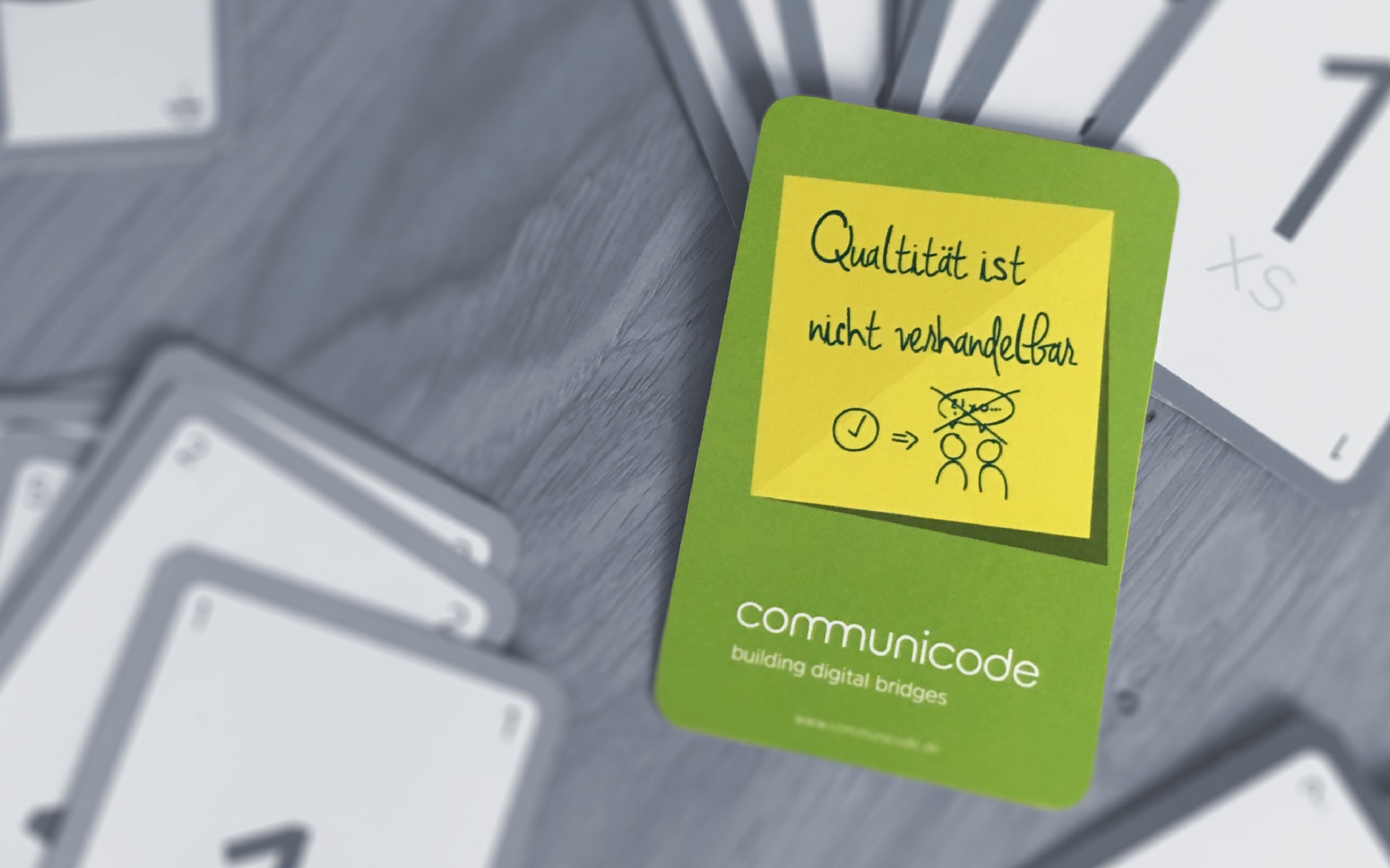 Ein schwarzweis Foto eines Kartendecks des Planning Pokers, bei dem eine Karte in grün mittig platziert ist