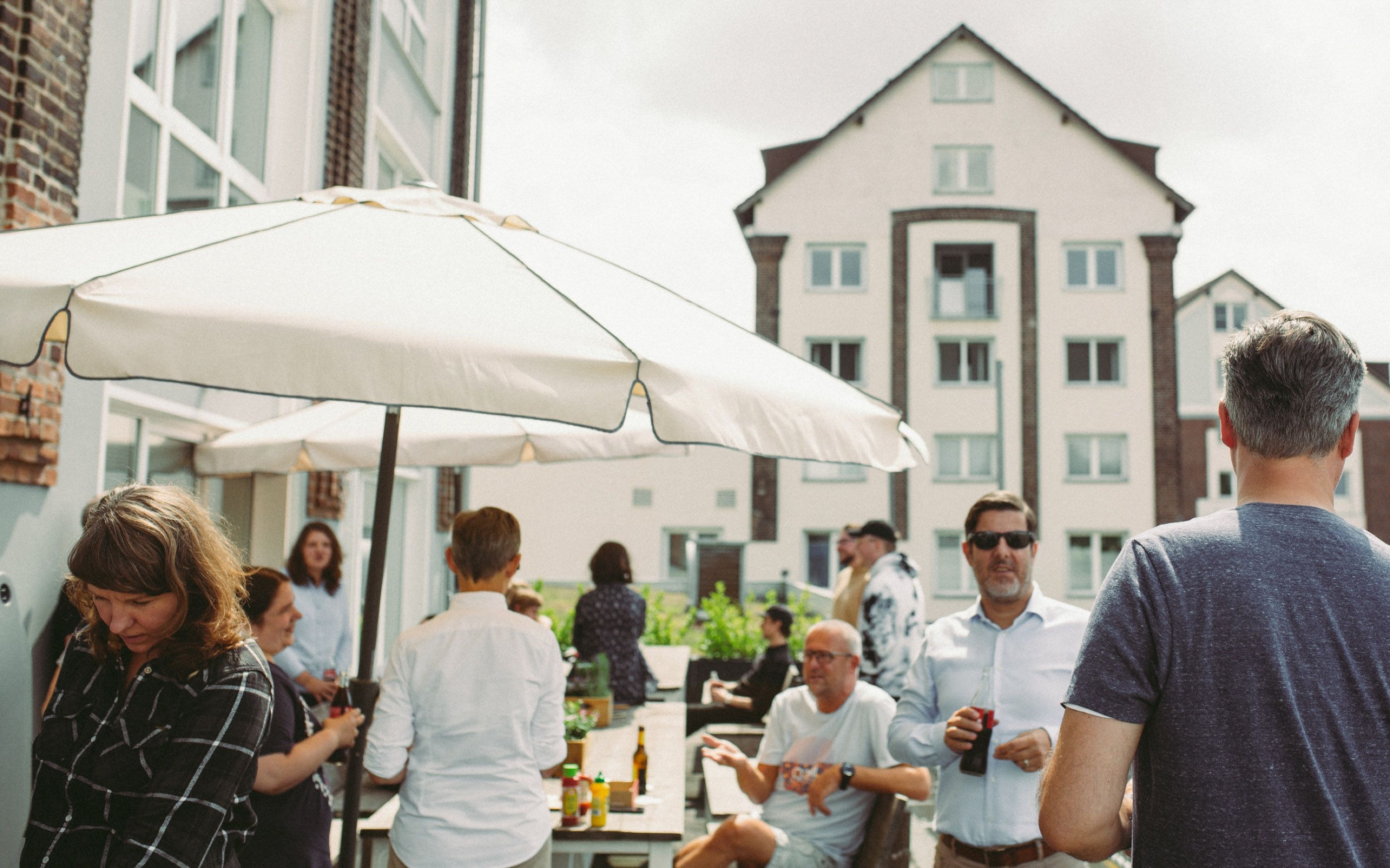 Foto mit Mitarbeitern auf einer Dachterrasse mit weißem Sonnenschirm