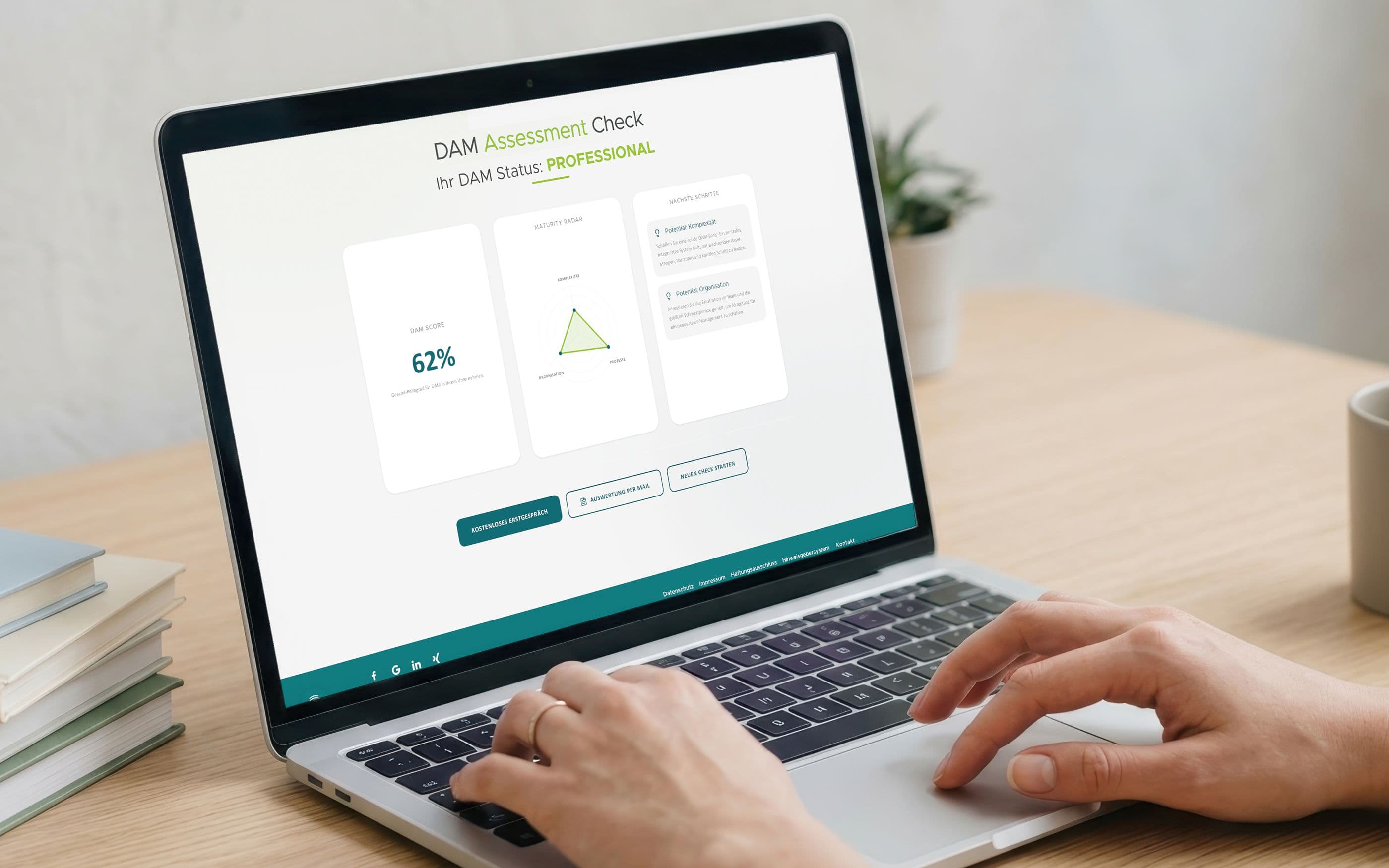 Person arbeitet an einem Laptop auf einem Schreibtisch. Auf dem Bildschirm ist ein „DAM Assessment Check“ mit dem Status „Professional“, einem Score von 62 %, einem Radar-Diagramm und Handlungsempfehlungen zu sehen.