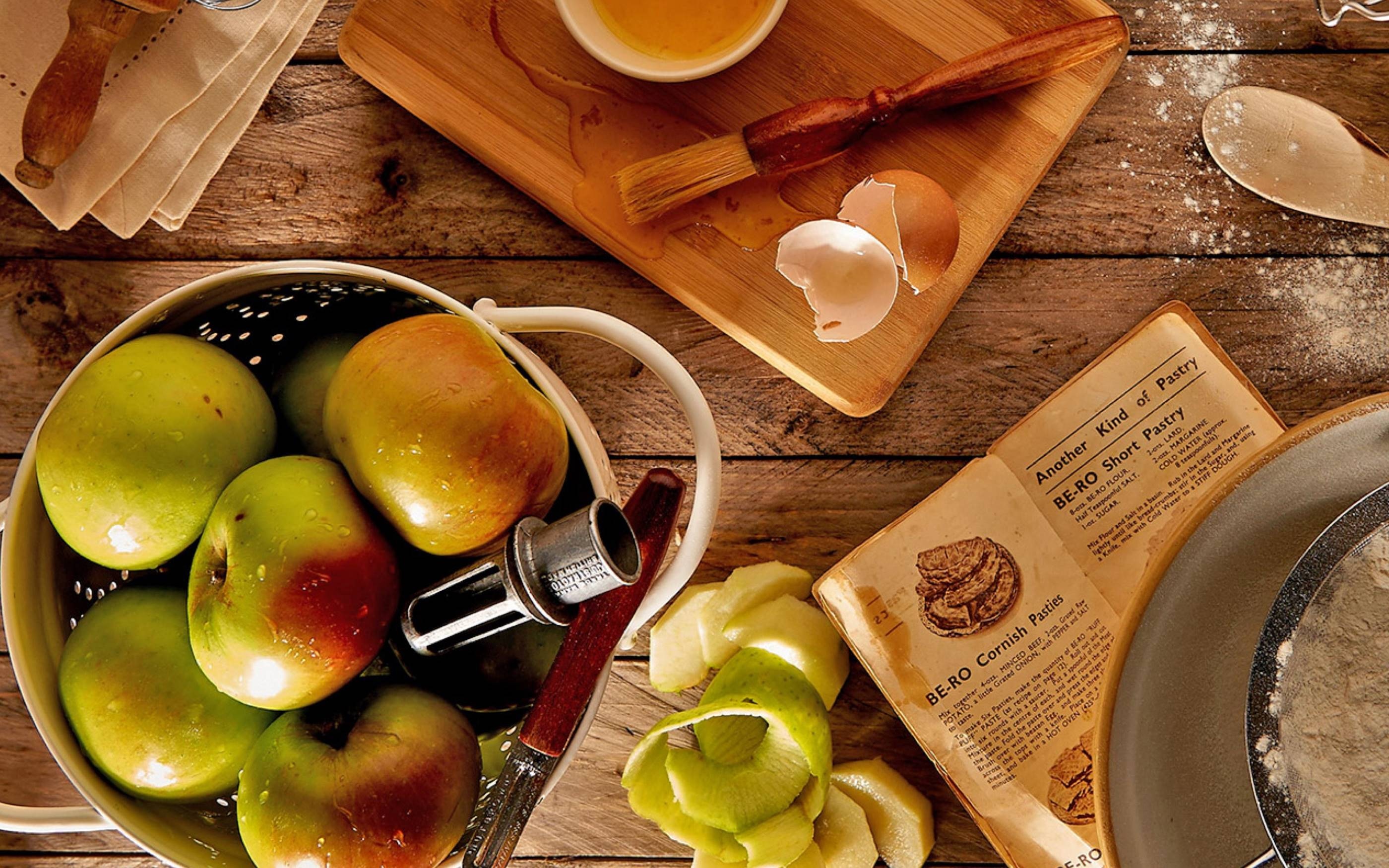 Tisch mit Rezepten, Äpfeln und Zutaten zum Backen