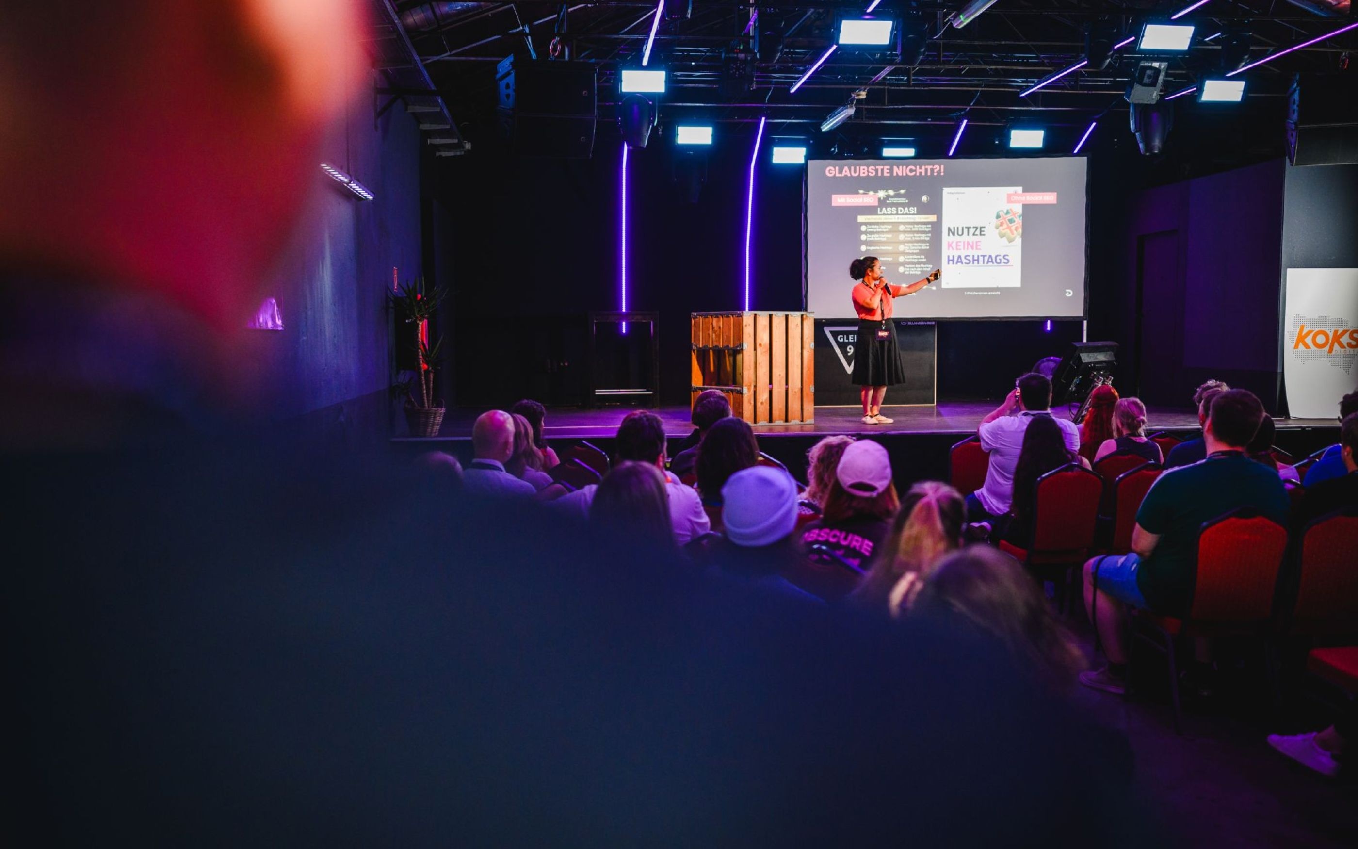 Foto aus dem Publikum heraus auf die Bühne der koks.digital auf der ein Vortrag gehalten wird.