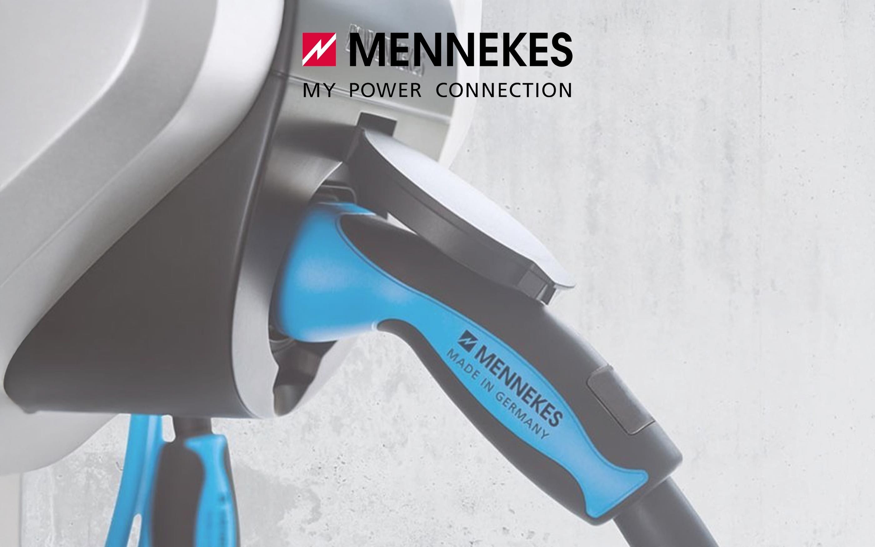 Close-up of a Mennekes charging station with a blue charging cable for electric vehicles plugged in. Above it is the Mennekes logo with the slogan “My Power Connection.”