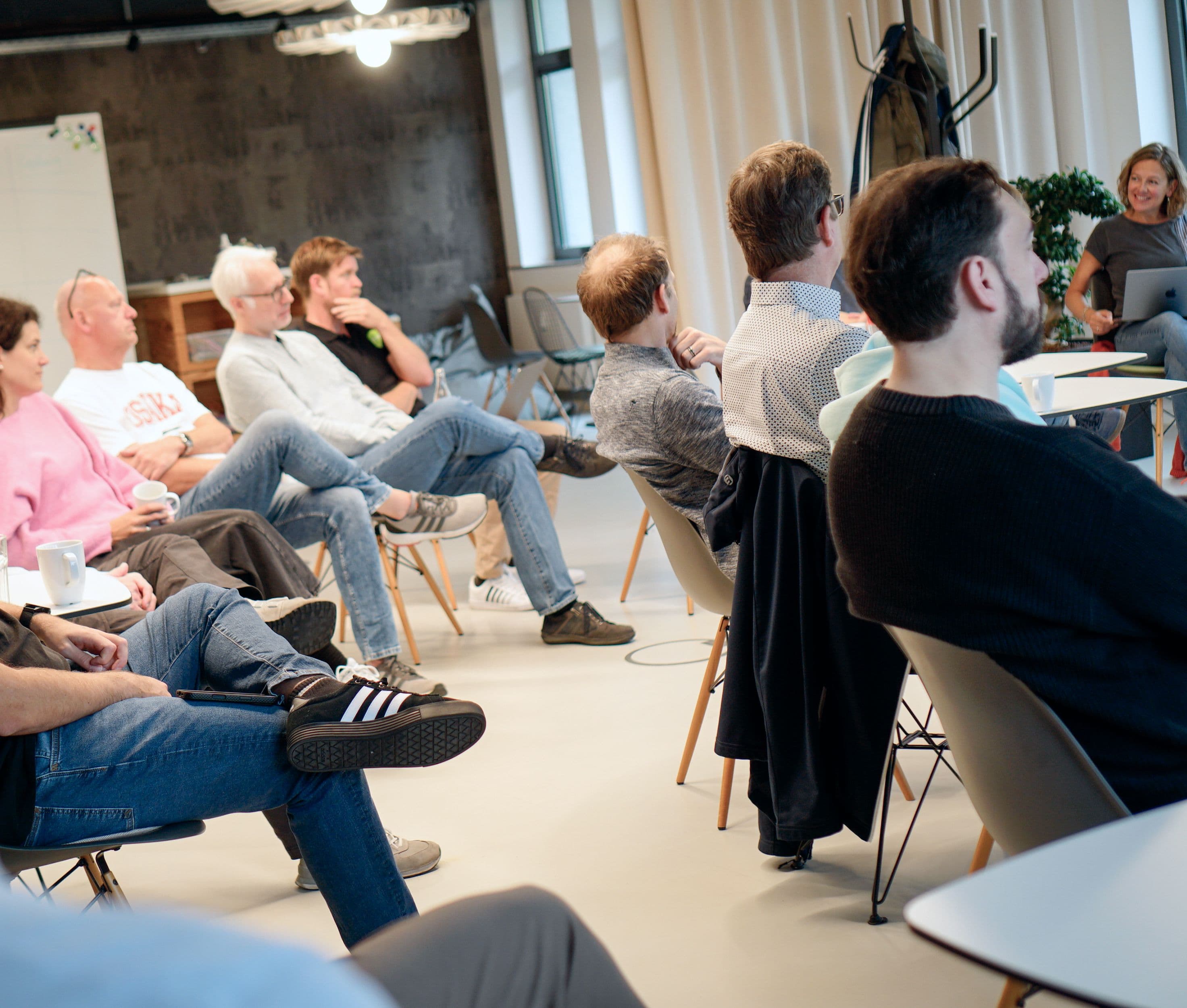 Teilnehmende sitzen in einem modernen Meetingraum und verfolgen eine Präsentation oder Diskussion im Rahmen eines Workshops, Meetups oder Fachvortrags.