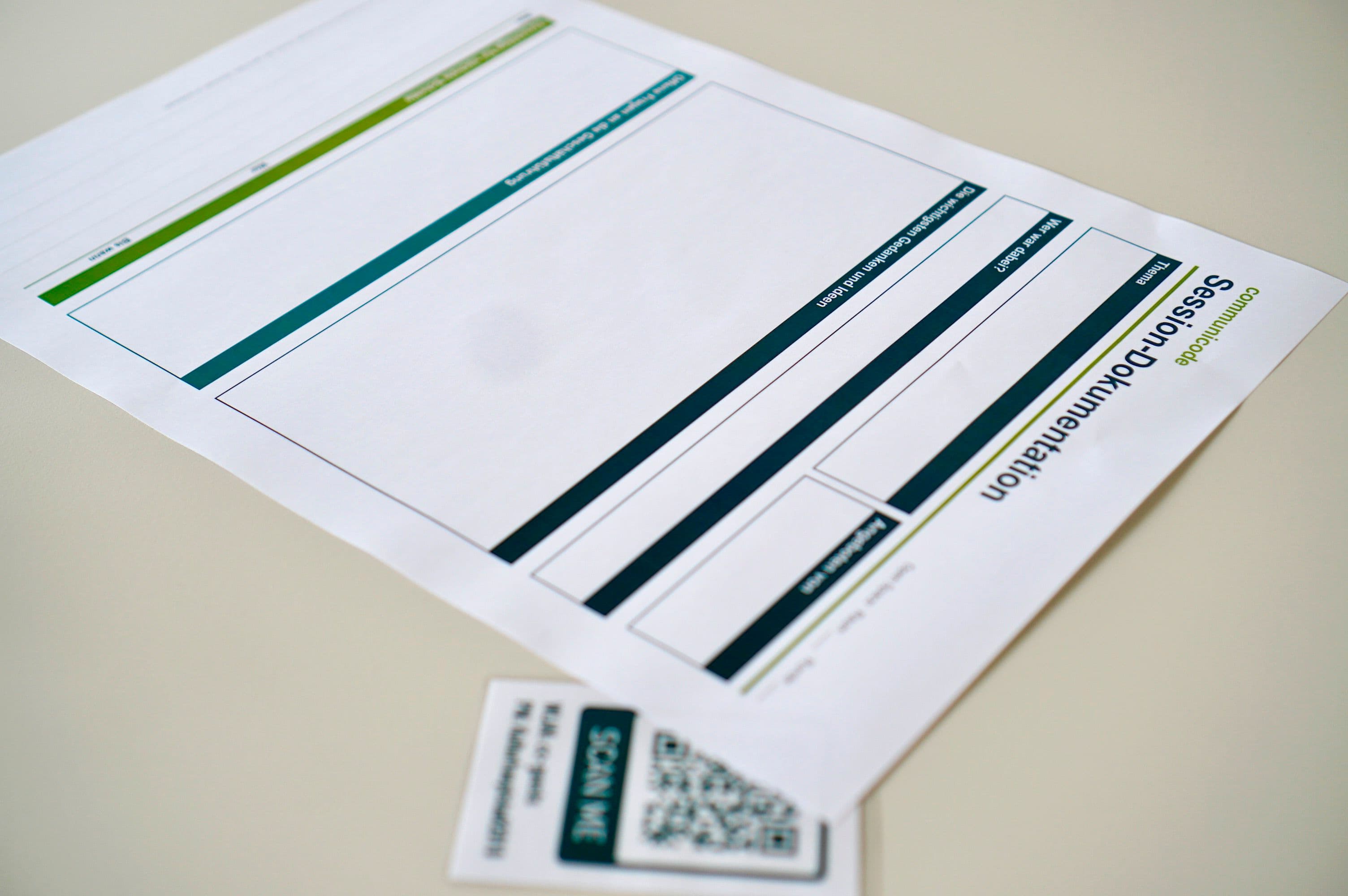 Session documentation template on a table next to a card with a QR code for digital participation.