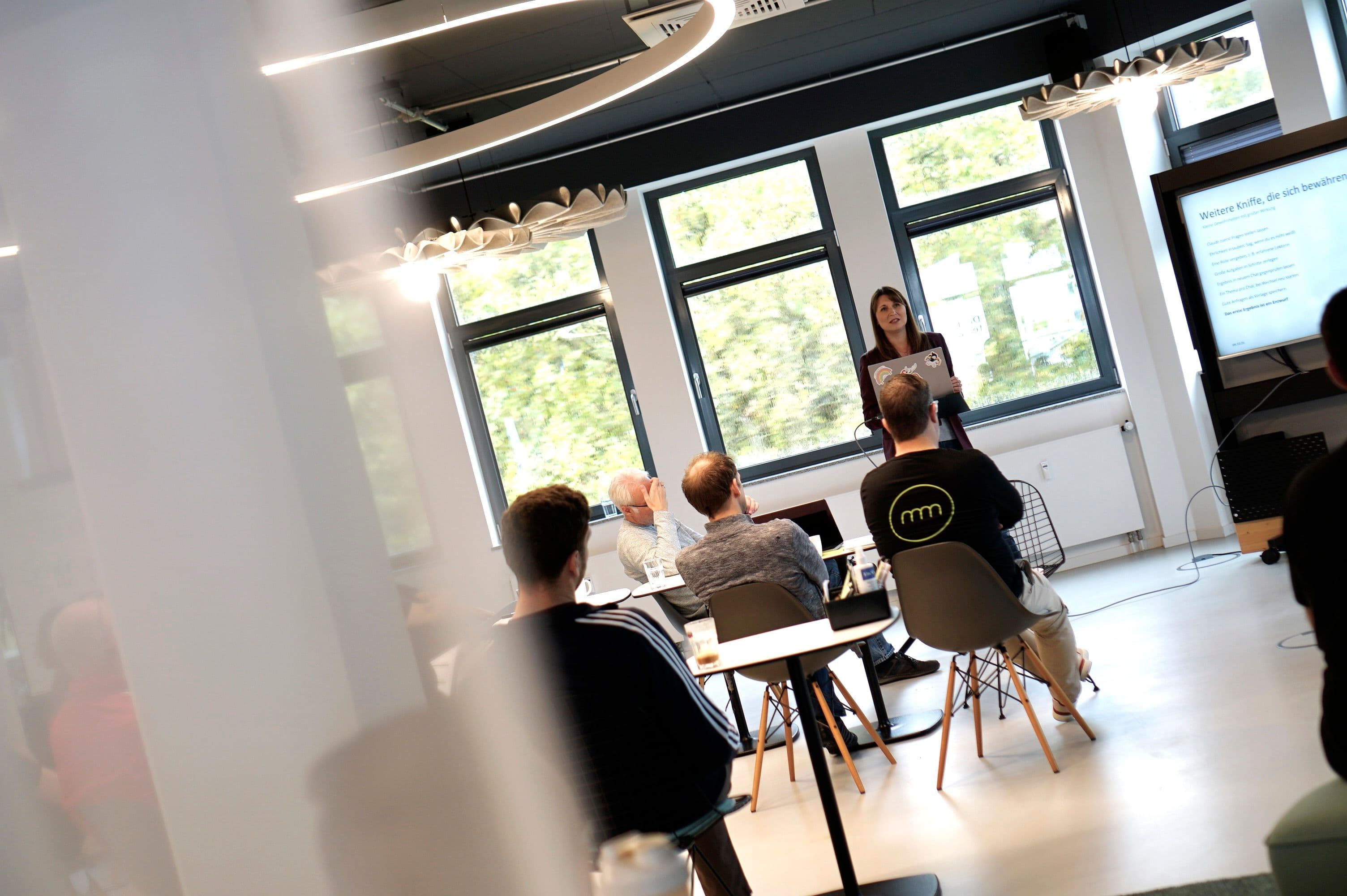Workshop oder Schulung in modernem Seminarraum mit Präsentation vor sitzendem Publikum.
