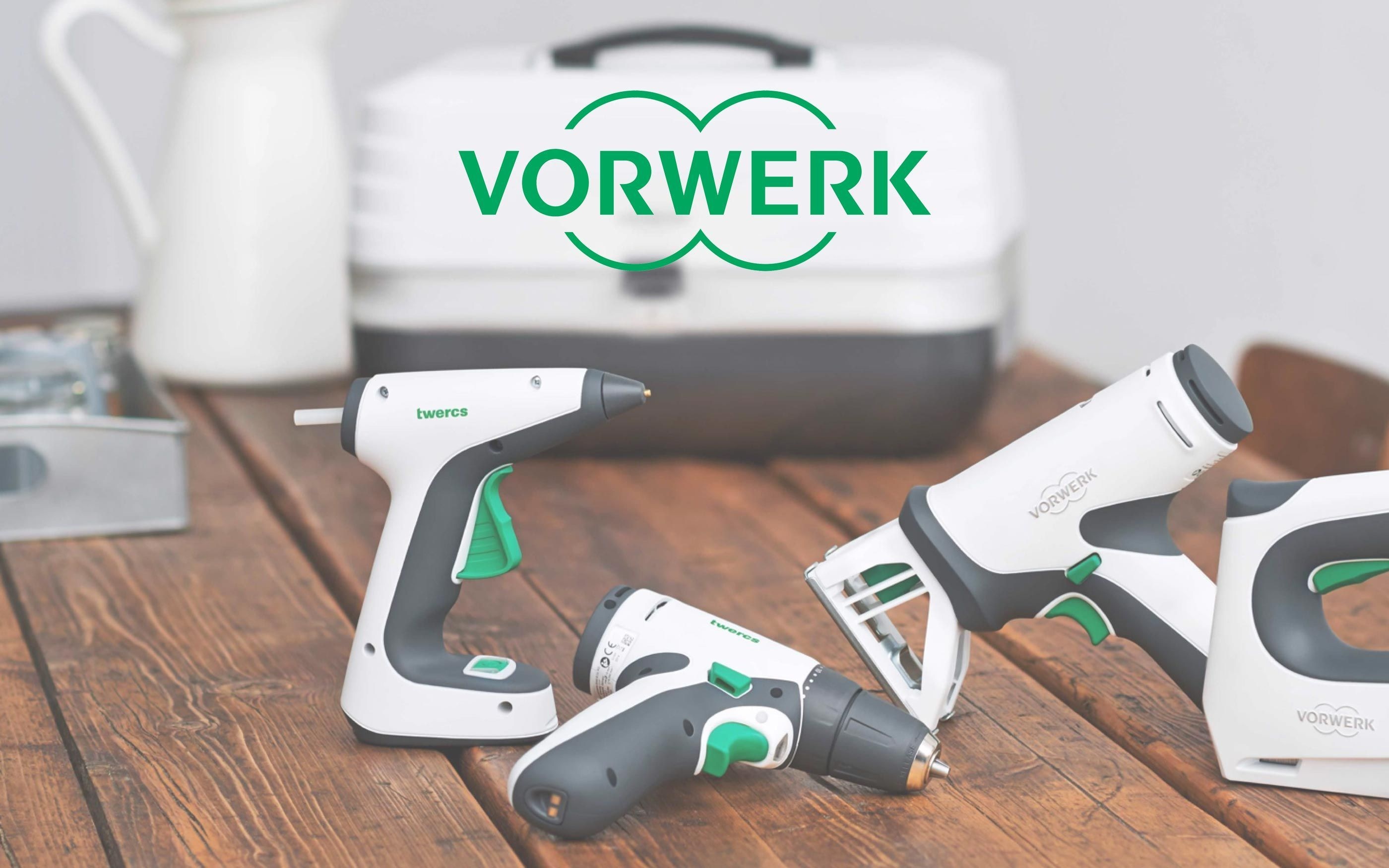 Vorwerk tool set on a wooden table with cordless devices such as a cordless screwdriver and hot glue gun in white and green. Toolbox with Vorwerk logo in the background.